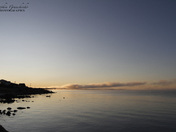 Beautiful sunrise over an arctic lake with fog on the horizon and sun peaking ov