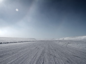 Partial sundog and winter ice road in the high arctic with a blue sky in the background, near Cambridge Bay, Nunavut, Canada