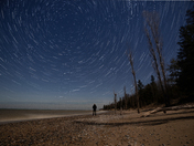 Person watching the stars with star trail effect on a beach, near Southampton, Ontario