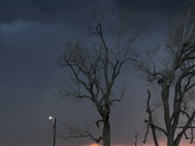 Storms coming in with unusual color around the sun, tornado damage from last month in the background.  